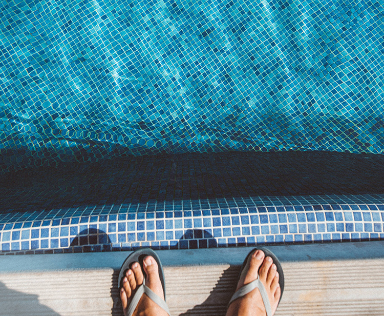 feet in flip sandals by pool edge